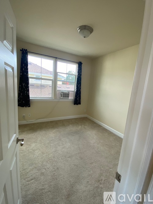 A room with a carpeted floor and a window with curtains.