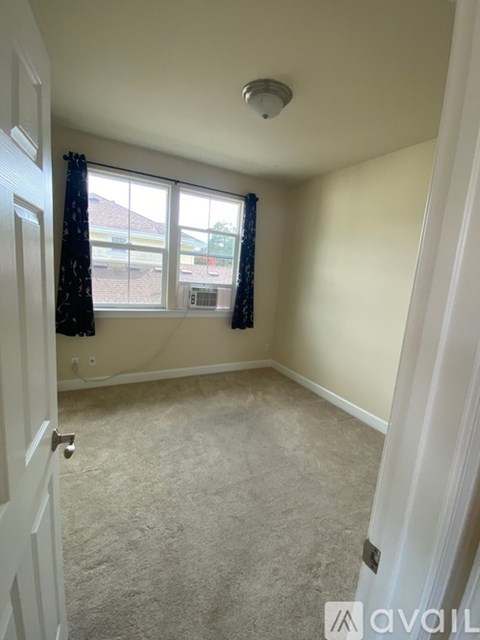 A room with a carpeted floor and a window with curtains.