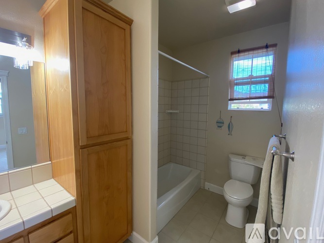 A bathroom with a toilet, sink, and wooden cabinet.