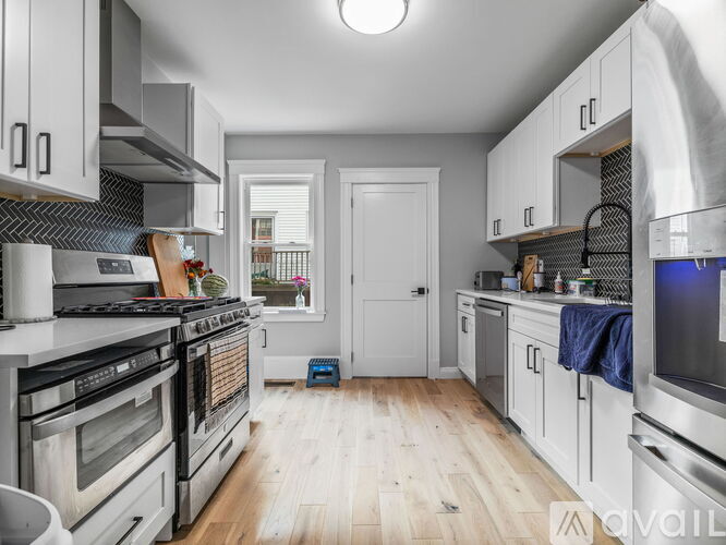 A kitchen with white cabinets and a wooden floor.