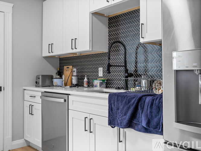 A kitchen with white cabinets and a black and white tiled backsplash.