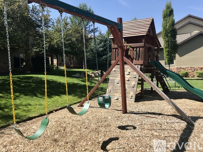 A playground with a swing set and a green slide.