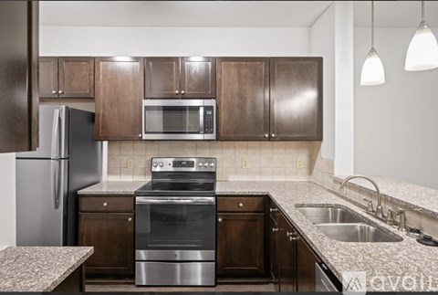 A kitchen with a stainless steel refrigerator, microwave, oven, and sink.