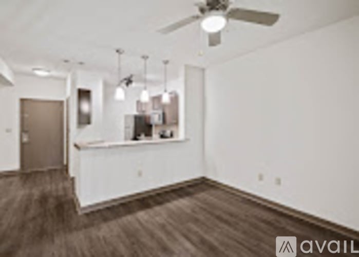 A room with a ceiling fan and a bar area.