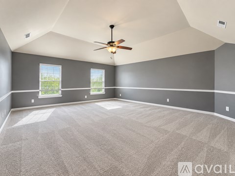 A spacious room with a ceiling fan and carpeted floor.