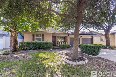 A tree in a circle of dirt stands in front of a house.