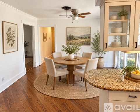 A dining room with a table set for four and a painting on the wall.