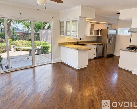 A kitchen with white cabinets and a wooden floor.