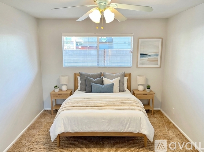 A bedroom with a bed, two lamps, and a ceiling fan.