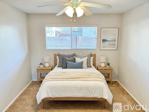 A bedroom with a bed, two lamps, and a ceiling fan.