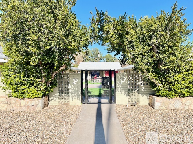 A stone wall with a gate in the middle and trees on both sides.