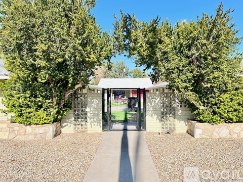 A stone wall with a gate in the middle and trees on both sides.