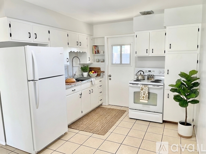 A white kitchen with a refrigerator, oven, and sink.
