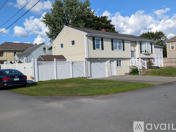 A two-story house with a white fence and a car parked in front.