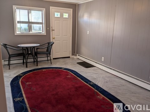A room with a table and chairs and a rug.