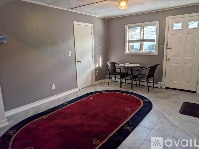 A room with a table and chairs and a rug.