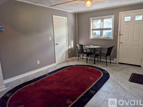 A room with a table and chairs and a rug.