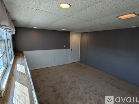 A room with grey walls and a carpeted floor is available for rent.