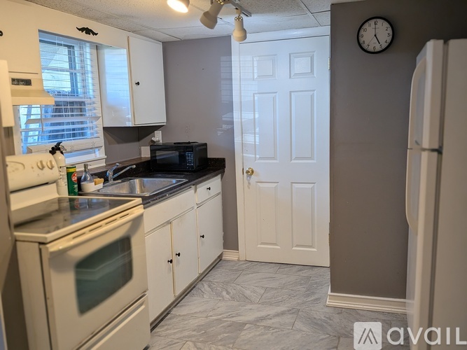 A kitchen with white cabinets and a black countertop.