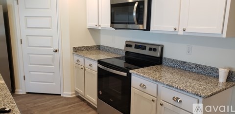 A kitchen with granite countertops and white cabinets.