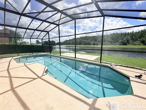 A glass enclosed pool with a view of a lake and trees.