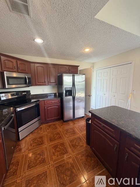 A kitchen with a refrigerator, microwave, oven, and sink.