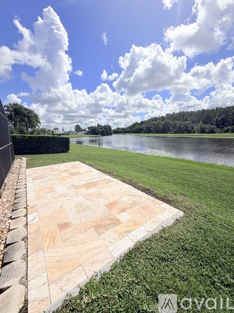 A stone pathway leads to a grassy area beside a lake.