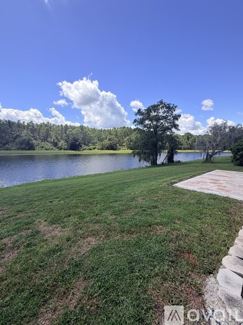 A serene landscape with a lake, trees, and a clear sky.
