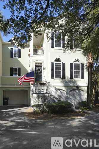 A white house with black shutters and an American flag on the front.