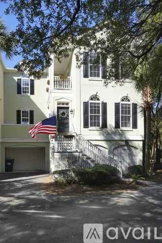 A white house with black shutters and an American flag on the front.