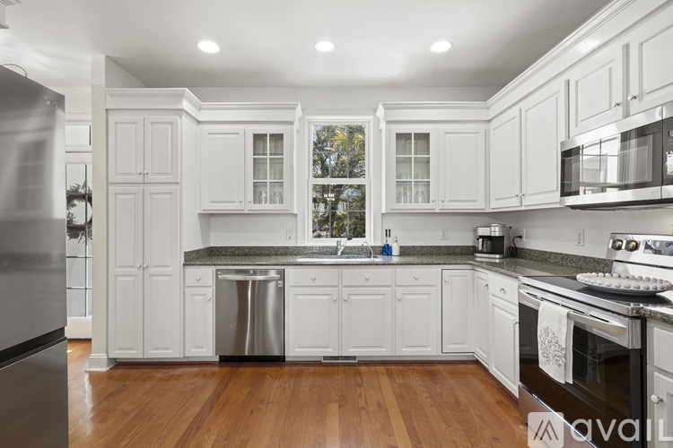A kitchen with white cabinets and a wooden floor.
