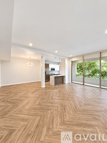 A spacious room with wooden flooring and a large window.