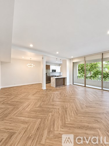 A spacious room with wooden flooring and a large window.