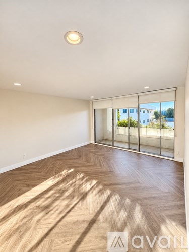 A room with wooden flooring and a window with a view of buildings outside.