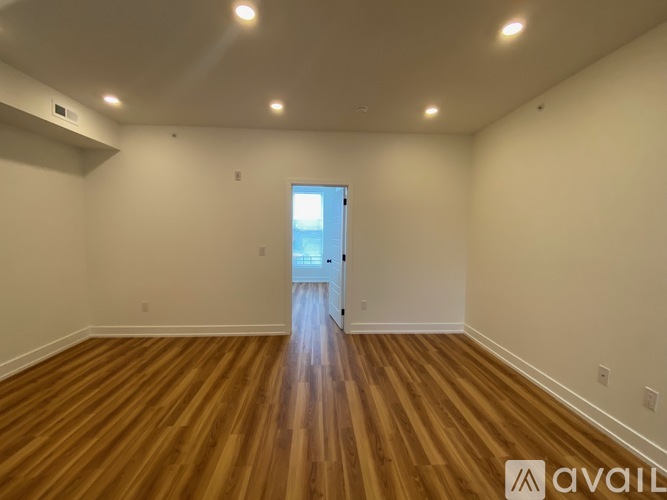 A room with wooden flooring and a doorway leading to another room.