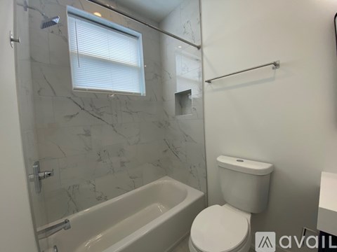 A bathroom with a toilet, tub, and towel rack.