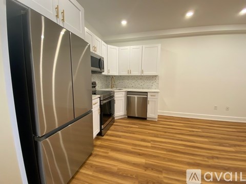 A kitchen with a stainless steel refrigerator and wooden floors.