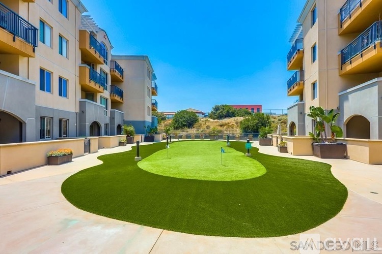 A small putting green is surrounded by apartment buildings.
