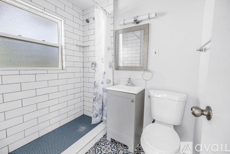 A white toilet sits next to a sink in a bathroom with white tiles.