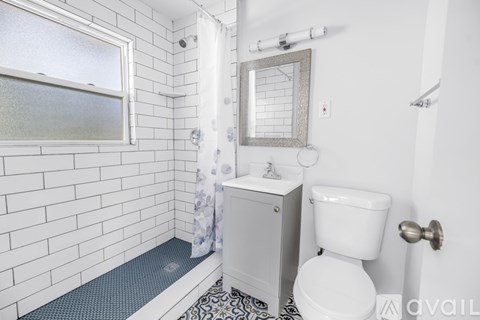 A white toilet sits next to a sink in a bathroom with white tiles.