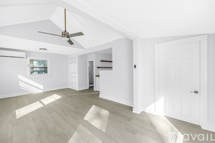 A spacious room with a ceiling fan and light wood flooring.