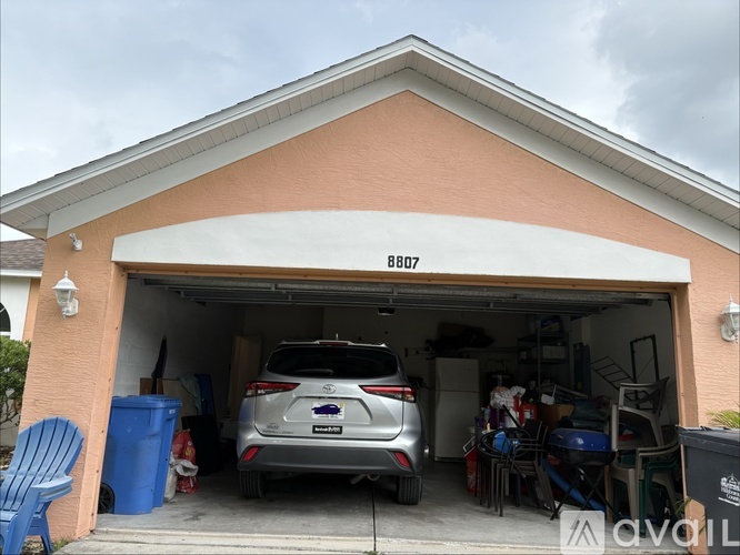 A car is parked in a garage with the number 8807 on the wall.