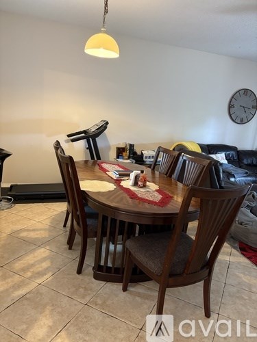 A dining room with a table set for four and a clock on the wall.