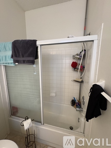 A bathroom with a white tub and a towel hanging on the door.