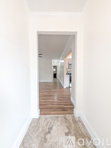 A hallway with a tiled floor and white walls.