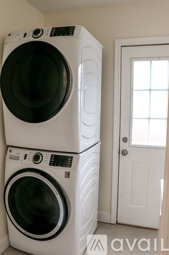 Two white front load washing machines stacked on top of each other.