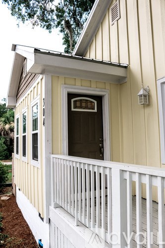 A small yellow house with a white porch.