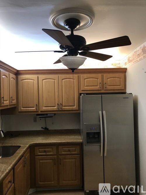 A kitchen with wooden cabinets and a stainless steel refrigerator.