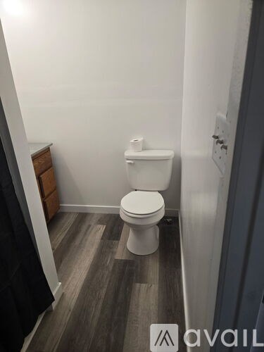 A bathroom with a toilet and a wooden cabinet.