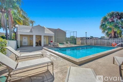 A poolside area with lounge chairs and a house in the background.